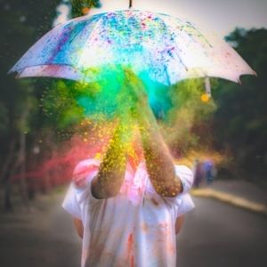 Eine Person hält einen Regenschirm und buntes Puder fliegt in der Luft